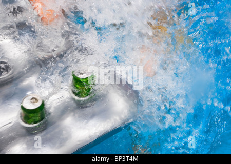 Bierdosen in Haltern auf eine aufblasbare Lilo mit Spalashing blauen Wasser. Schöne abstrakte Sommer Bild Stockfoto