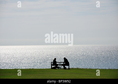 Paar, sitzen auf Bank, The Greensward, Frinton-on-Sea, Essex, England, Vereinigtes Königreich Stockfoto