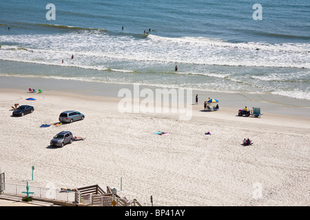 Besucher fahren Autos am Strand zum Surfen, Sonnen und spielen in den Wellen des Atlantischen Ozeans in Daytona Beach Shores, Florida Stockfoto