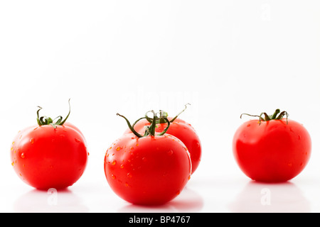 eine Tomate und drei Tomaten auf weißem Hintergrund Stockfoto