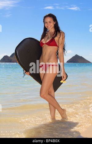 schöne junge Frau am Strand auf Hawaii mit ihrem Surfbrett Stockfoto