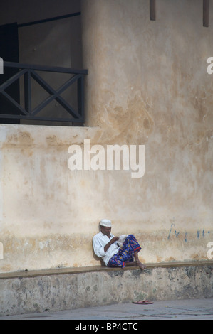 Ein Mann sitzt in der Hauptansicht von lamu Platz vor dem alten Fort, Kenia, Afrika Stockfoto