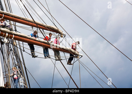 Mitglieder der Besatzung eines Quadrats manipuliert Segelschiff arbeitet an der mittleren Hof (Spar) von einem der Masten. Stockfoto