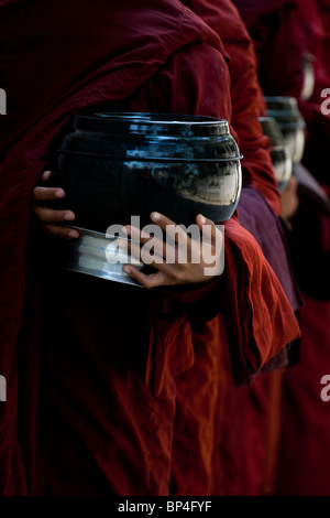 Junge Mönche stehen in der Schlange, Lebensmittel aus der Community rund um das Mahagandayon Kloster in Amarapura, Myanmar zu erhalten. Stockfoto