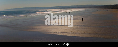 Ein wunderschöner Sandstrand bei Sonnenuntergang mit Silhouetten von Menschen Stockfoto