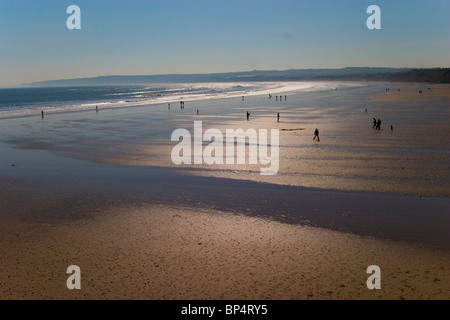 Ein wunderschöner Sandstrand bei Sonnenuntergang mit Silhouetten von Menschen Stockfoto