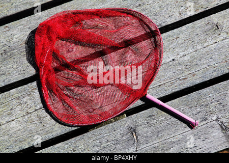 Hell rosa rot Kind Angeln oder Schmetterling Netto liegen auf einem hölzernen pier Stockfoto