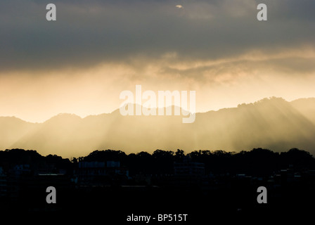 Sonnenschein durch graue Wolken und Licht Abstufung Berge hinauf. Stockfoto