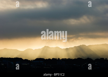 Sonnenschein durch graue Wolken und Licht Abstufung Berge hinauf. Stockfoto