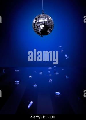 Gebrochene Discokugel mit Stücken des Spiegels auf eine glänzende Glasboden herunterfallen auf blauem Hintergrund isoliert Stockfoto