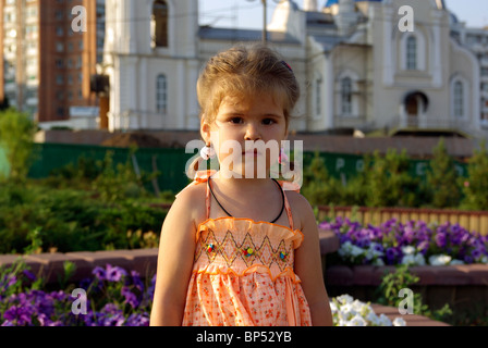 Kleines Mädchen im Park. Blume und Kirche im Hintergrund. Stockfoto