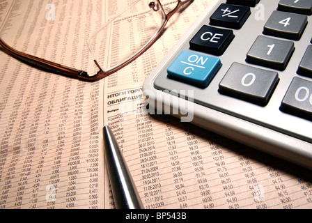 Gläser, professionelle Taschenrechner und Stahl Stift auf Zeitung. Stockfoto