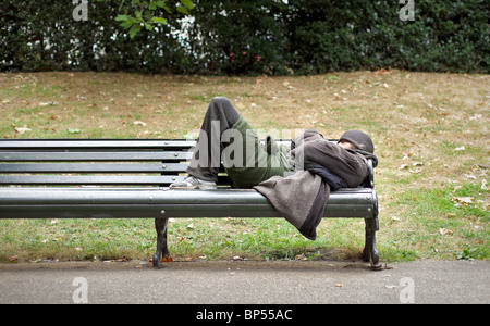 Ein Obdachloser schläft auf einer Bank im Zentrum von London, England Stockfoto