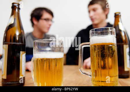 Flaschen und Gläser Bier mit zwei junge Männer im Hintergrund Stockfoto