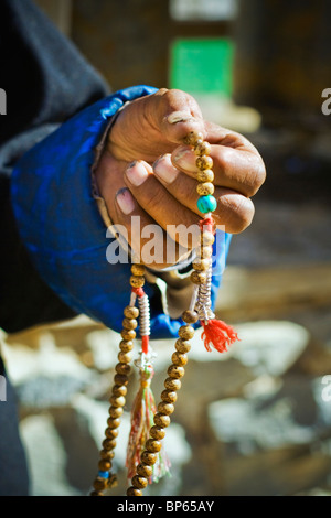 Ein traditionell gekleideter tibetischen Pilger hält sein Gebet/Meditation/Mantra-Perlen Stockfoto