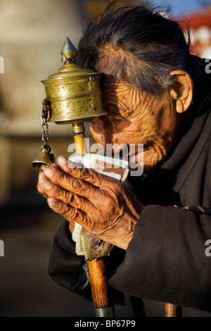 Eine tibetische Frau Pilgram betet mit Gebetsmühle, in Richtung Sonnenuntergang Barkhor Square, Lhasa, Tibet, China. 2010 Stockfoto