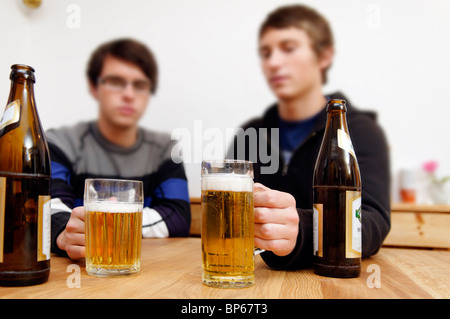 Flaschen und Gläser Bier mit zwei junge Männer im Hintergrund Stockfoto