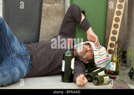 betrunkener Mann liegen in der Nähe von Mülleimer in Stadtstraße Stockfoto