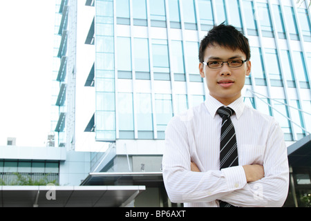 Ein Asian Business executive steht vor einem Bürogebäude Stockfoto