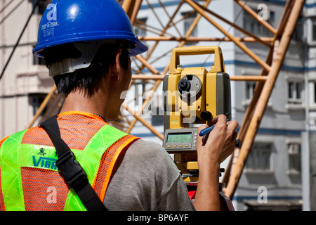 Ein Ingenieur unter Lesungen aus einem Theodolit auf einer Baustelle in Hong Kong. Stockfoto