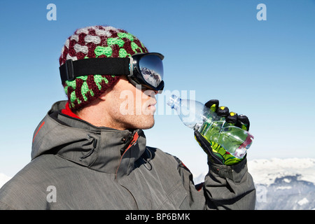 Junger Mann in Ski tragen Trinkwasser aus einer Flasche, Profil Stockfoto
