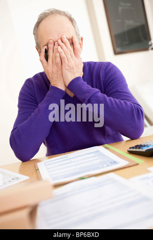 Mann sucht besorgt beim Ausfüllen seiner Steuererklärung Stockfoto