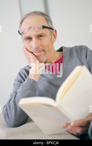 Porträt eines Mannes, der ein Buch hält und lächelnd Stockfoto