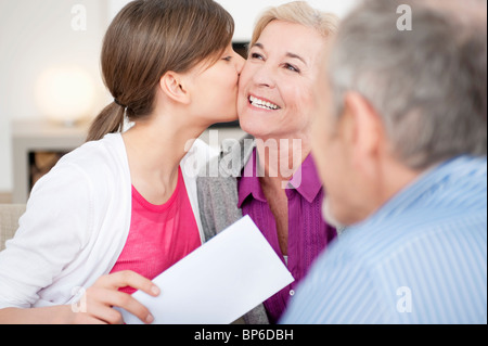 Mädchen küssen ihrer Großmutter mit ihrem Großvater neben ihnen sitzen Stockfoto