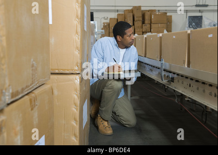 Mann, die Inspektion Boxen auf Förderband im Auslieferungslager Stockfoto