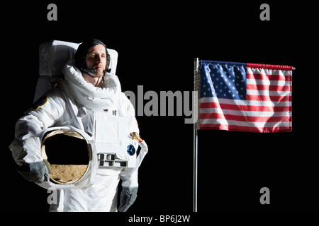 Ein Astronaut hält seinen Helm stand neben einer amerikanischen Flagge, Porträt Stockfoto