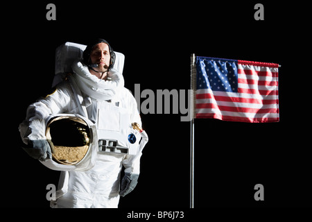 Ein Astronaut hält seinen Helm stand neben einer amerikanischen Flagge, Porträt Stockfoto