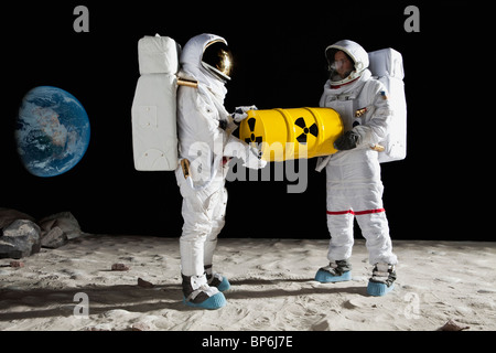 Zwei Astronauten auf der Mondoberfläche mit einer Trommel toxisches material Stockfoto