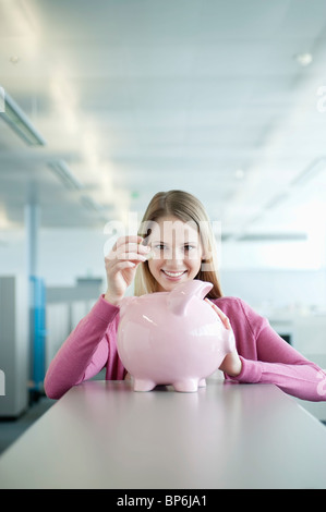 Geschäftsfrau Münzeinwurf in ein Sparschwein Stockfoto