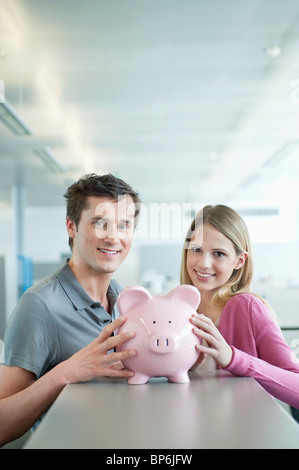 Führungskräfte in Unternehmen hält ein Sparschwein und lächelnd Stockfoto