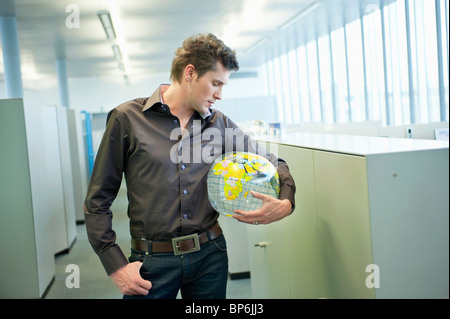 Geschäftsmann hält einen Globus und denken in einem Büro Stockfoto