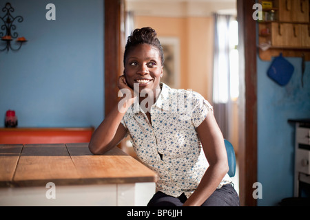 Eine junge Frau sitzt an einem Tisch in der heimischen Küche Stockfoto