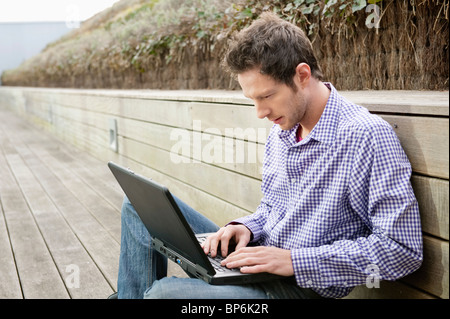 Mann mit einem Laptop auf einem Holzsteg Stockfoto