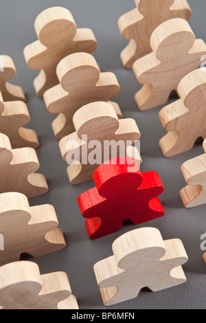 Ein rotes Holz Strichmännchen mit einer Gruppe von unbemalte Figuren aus Holz stick Stockfoto