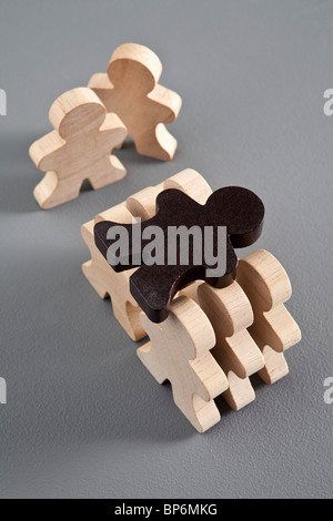 Sechs unbemalte Figuren aus Holz Stick trägt eine braune hölzerne Strichmännchen Stockfoto