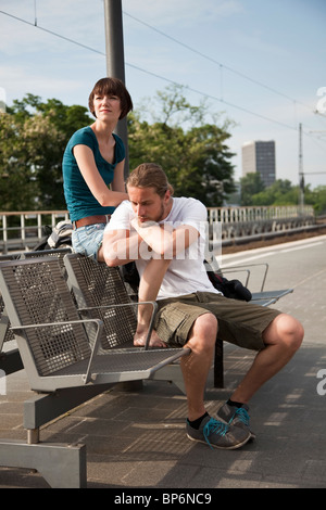 Ein gelangweilter Backpacker paar warten auf ihren Zug auf einem Bahnsteig Stockfoto