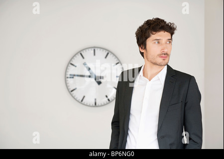 Geschäftsmann, steht man vor einer Uhr Stockfoto