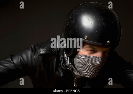 Ein Mann trägt einen Helm, Halstuch Maske und Leder Jacke Stockfoto