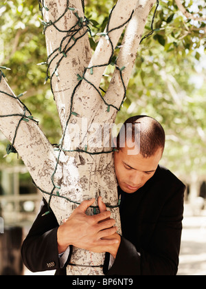 Ein Geschäftsmann umarmt einen Baum Stockfoto