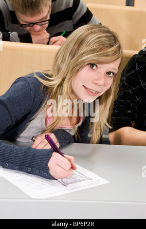 Porträt eines Teenagers tun ein Arbeitsblatt in der Klasse, in die Kamera Lächeln Stockfoto