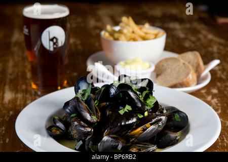 Moules Mariniere mit Pommes Frites und ein Pint Bier in einer Kneipe-Tabelle Stockfoto