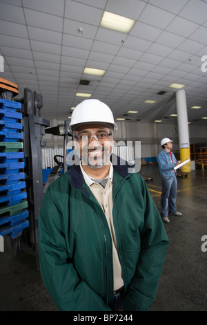 Fröhlicher Mensch stehen in Fabrik, Hart Hut Stockfoto