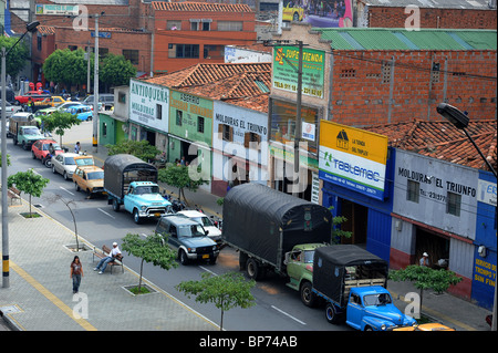 Verkehr und geparkte Fahrzeuge auf Straßen außerhalb Stores in Medellin, Südamerika Stockfoto