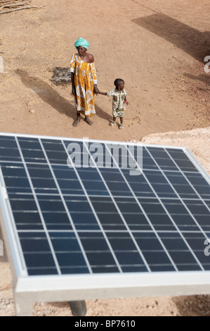 Westafrika Mali Sonnenkollektor auf dem Dach des solar powered Akku aufladen Station im Dorf Dialkoro, Frau mit Kind Stockfoto