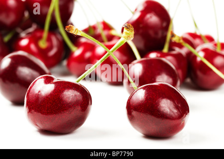 zwei Kirschen vor vielen auf weißem Hintergrund Stockfoto