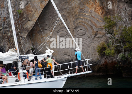 Touristen auf einer Yacht anzeigen die Maori Carving in Mine Bay, Taupo Stockfoto